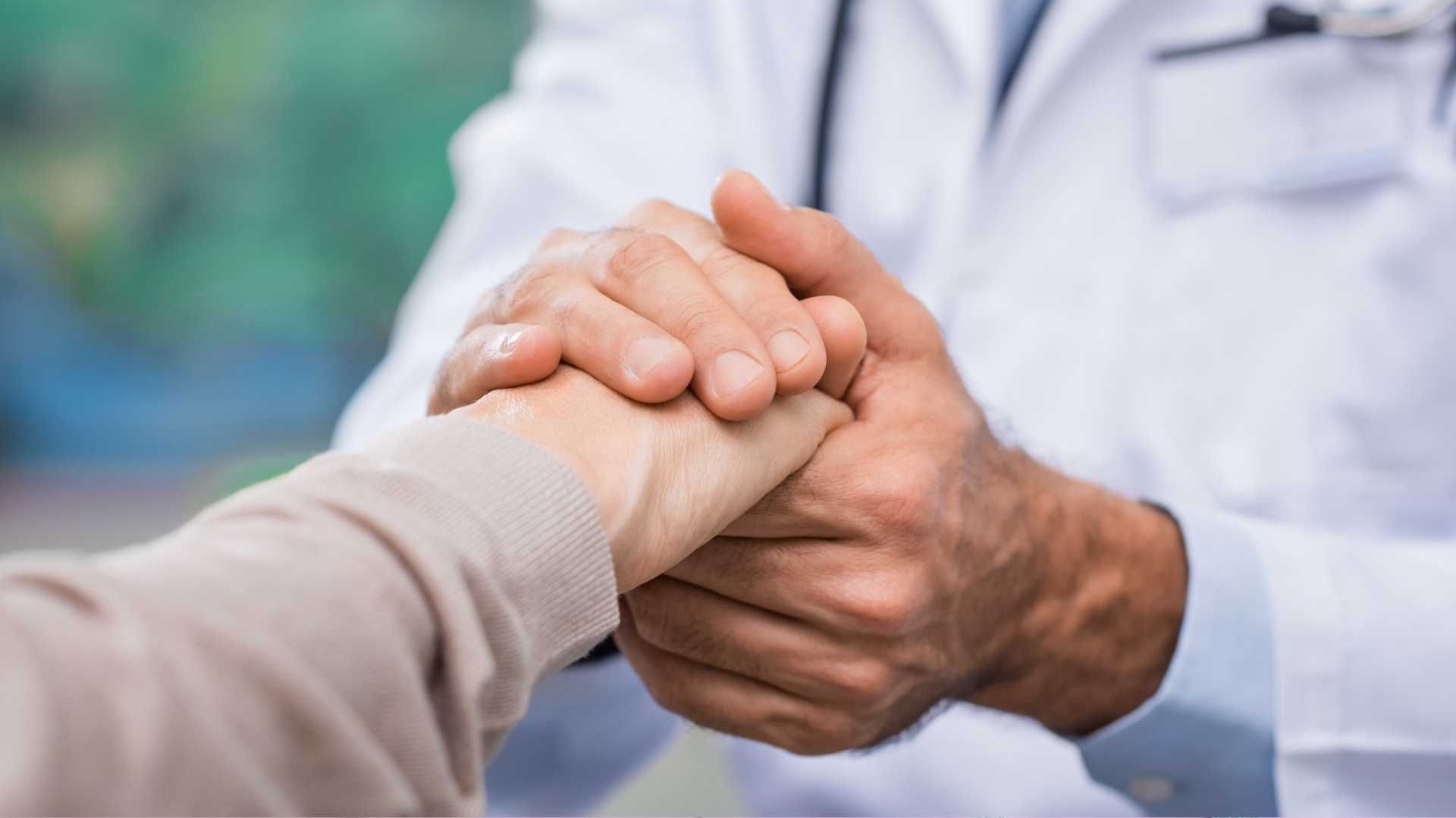 A doctor is holding the hand of a patient.