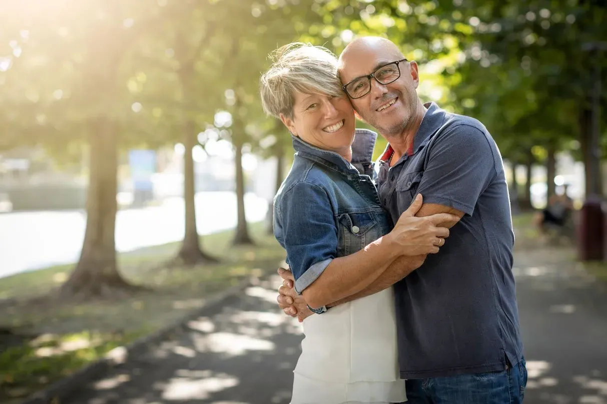 happy mature couple standing and smiling in a park