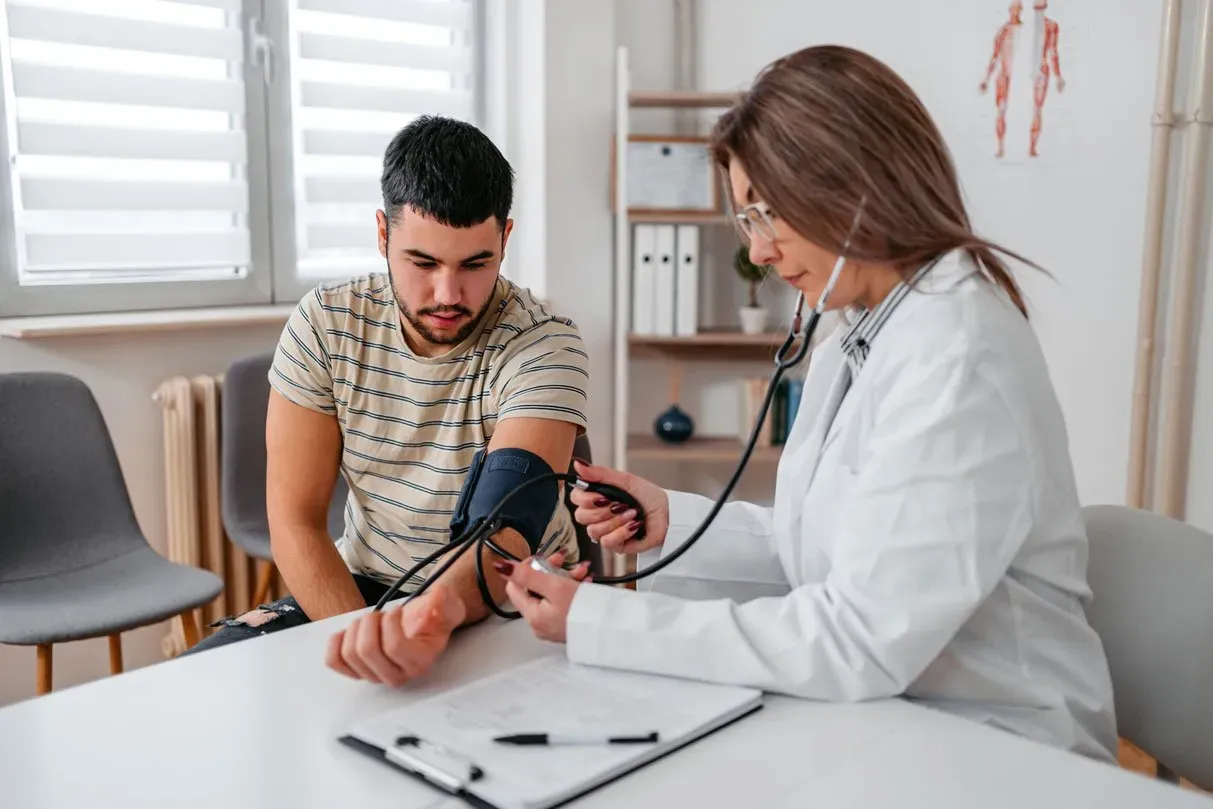 doctor measuring blood pressure of a young teenage patient