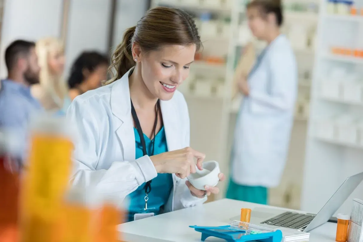 smiling pharmacist focuses on her mortar and pestle as