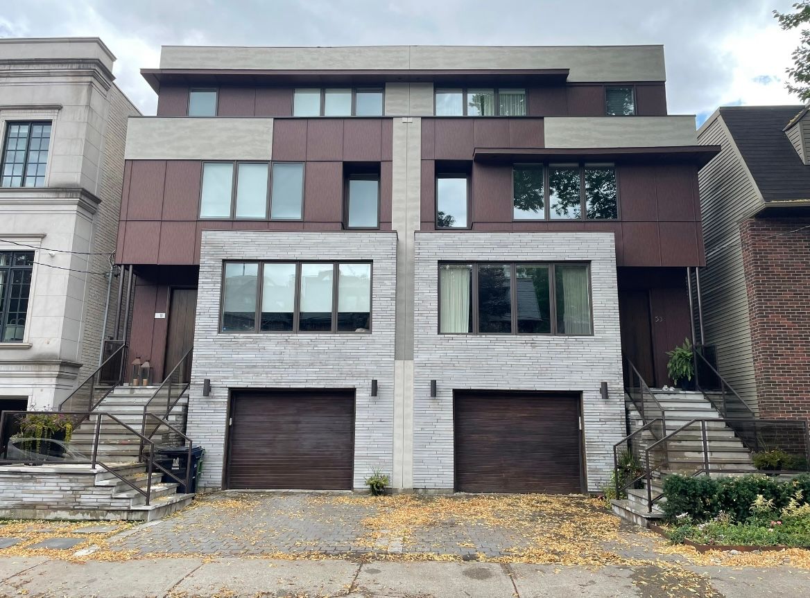 Modern townhouses with brick and brown siding, two garages, and multiple windows.