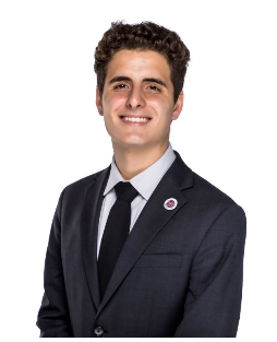 A young man in a suit and tie is smiling for the camera