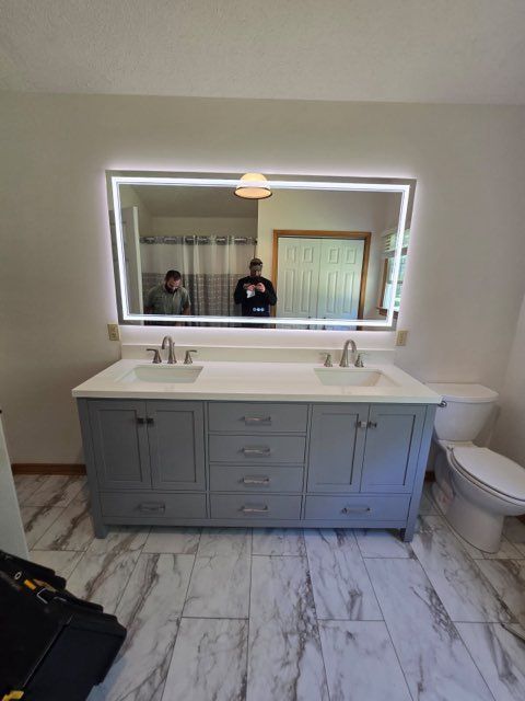 Modern bathroom vanity with double sinks, large backlit mirror, and marble-pattern tile floor