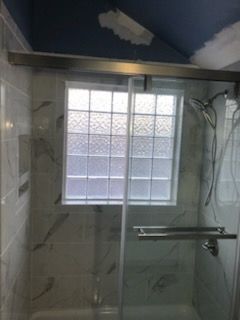 Bathroom with tiled shower walls, frosted window, and a glass shower door.