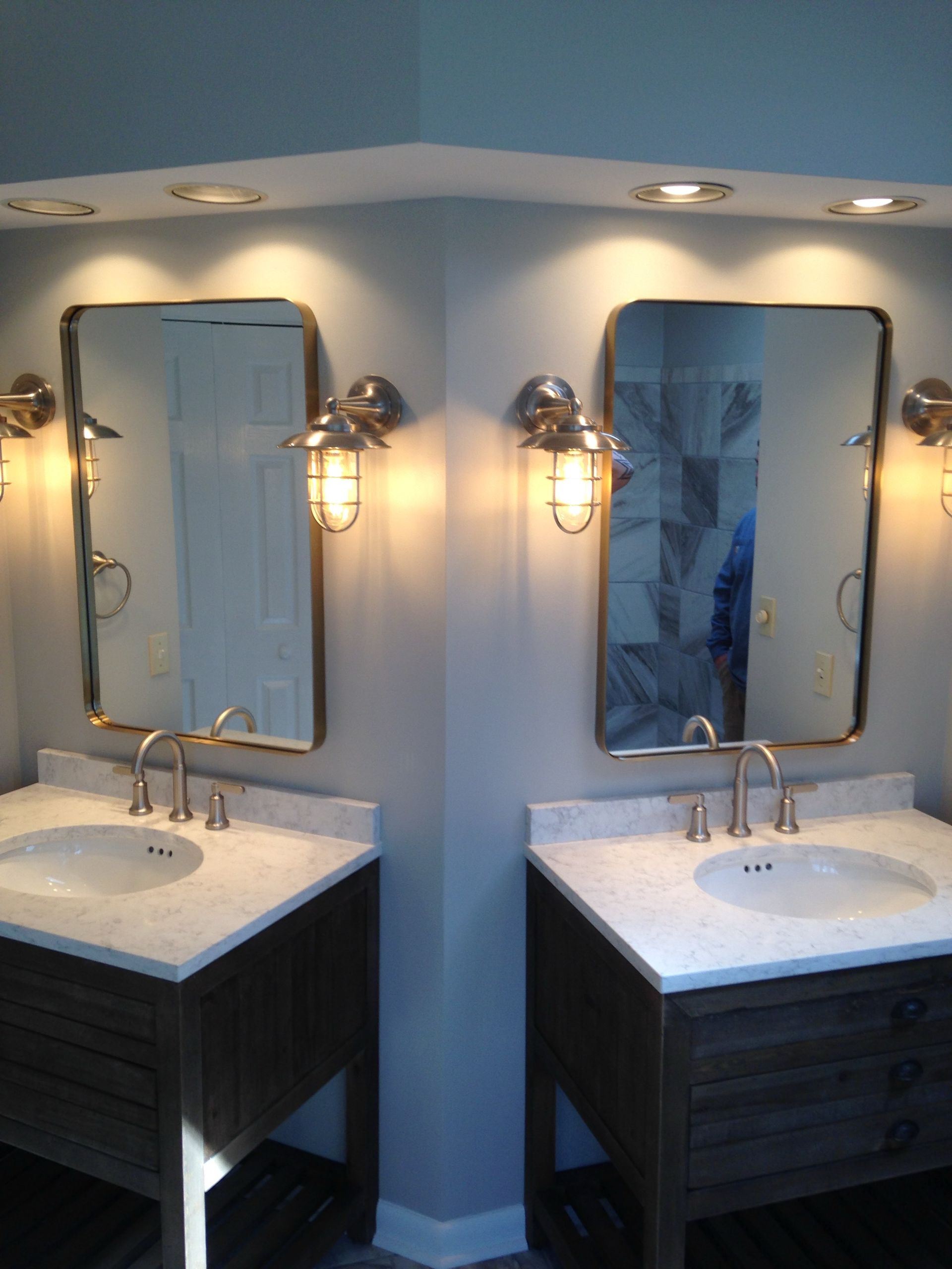 Two bathroom vanities with mirrors, sinks, and wall sconces in a softly lit room
