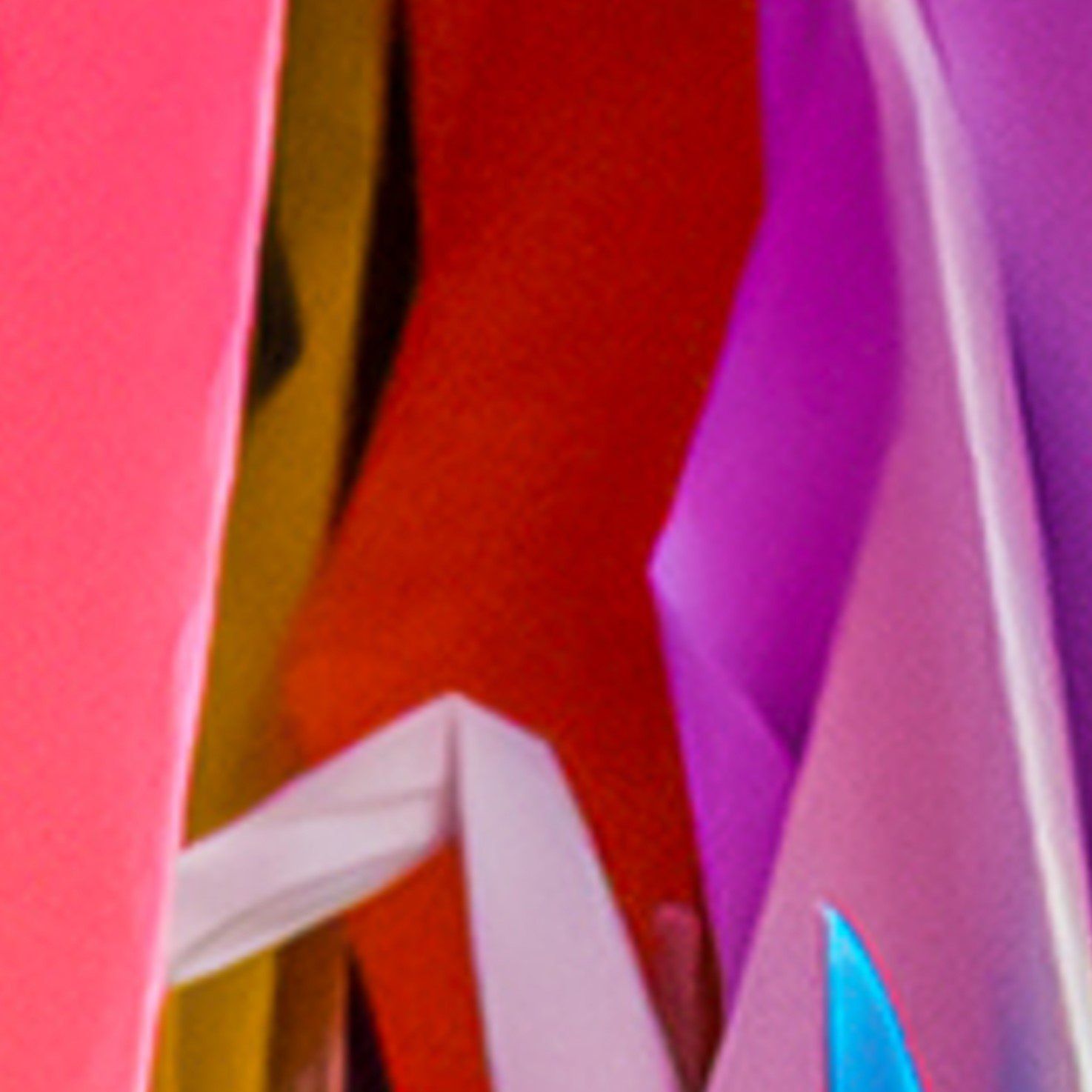 Close-up van overlappende vouwen van helder, kleurrijk papier in tinten roze, oranje, rood, paars en blauw.