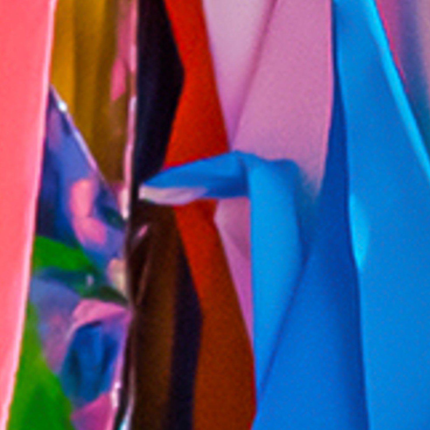 Een levendige, abstracte compositie van gevouwen, overlappende vellen papier in heldere tinten roze, blauw, rood, groen en goud.