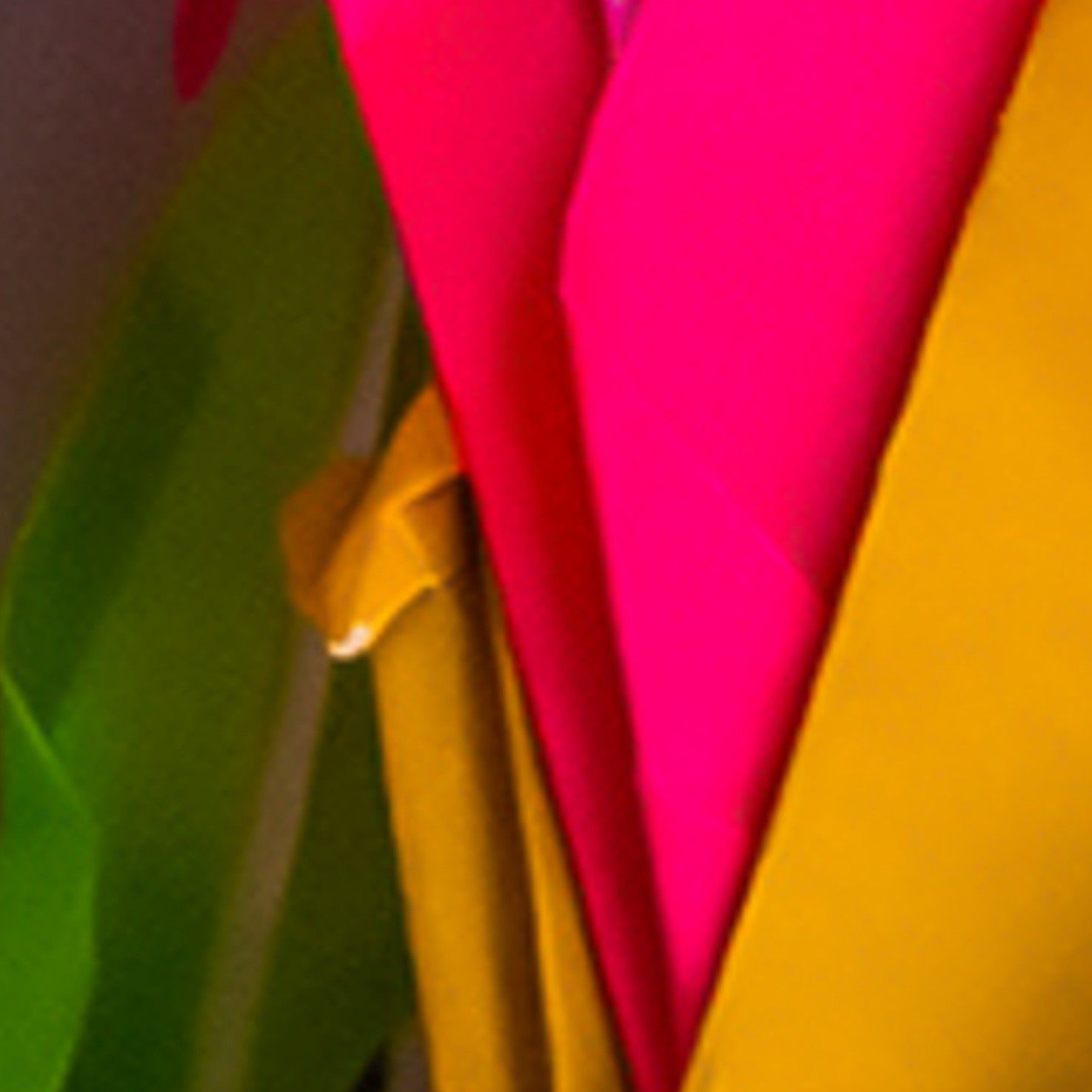 Detailopname van overlappende papiervouwen in levendig groen, felroze en mosterdgeel.