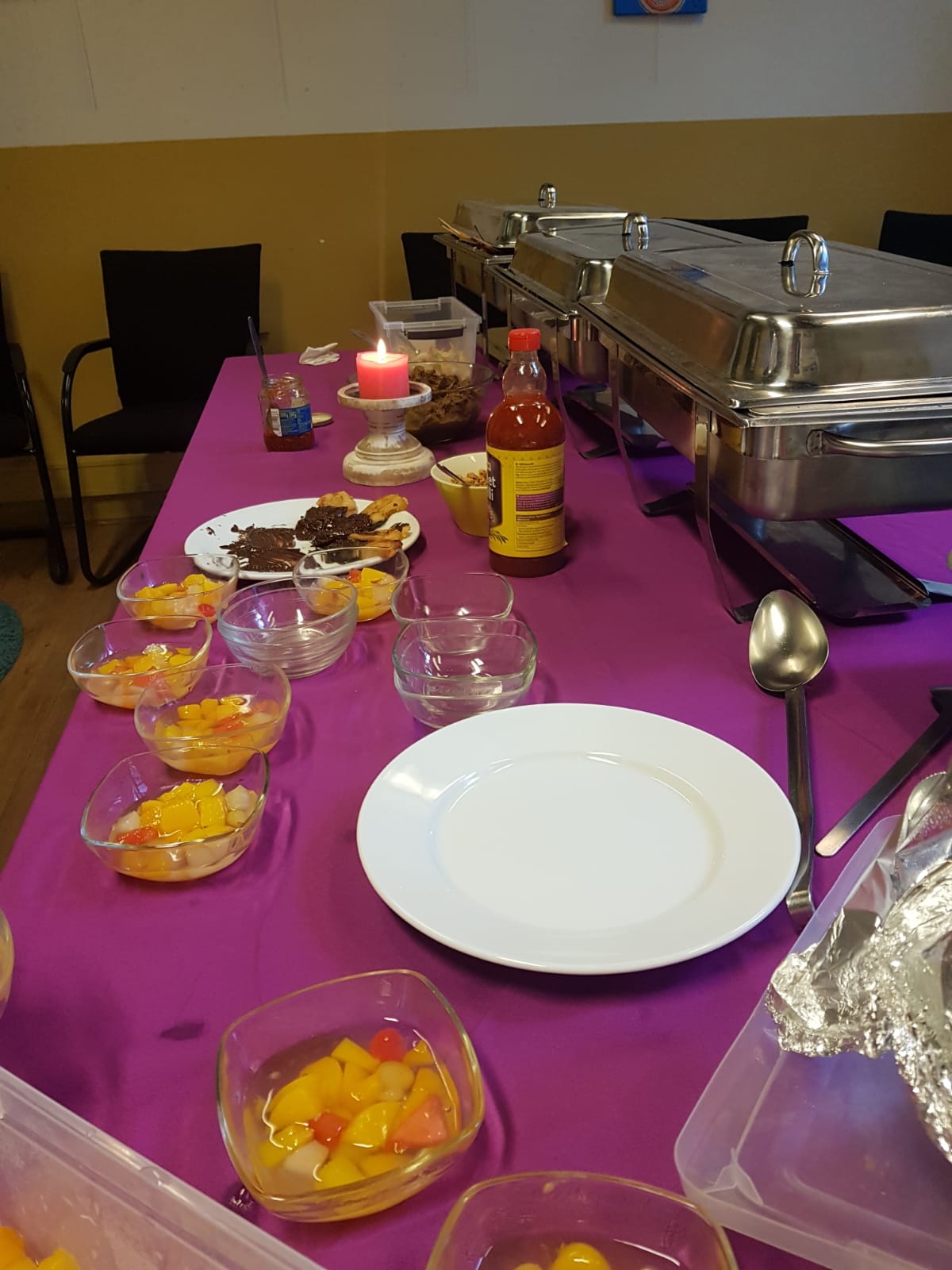Buffettafel met een felpaars tafelkleed, met kleine schaaltjes fruit, een dienblad en een kaars.