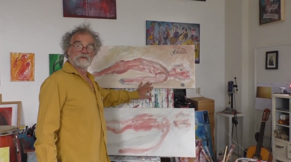 Een kunstenaar in een geel shirt staat in een atelier en wijst naar twee rechthoekige doeken met roodfigurige schilderijen.