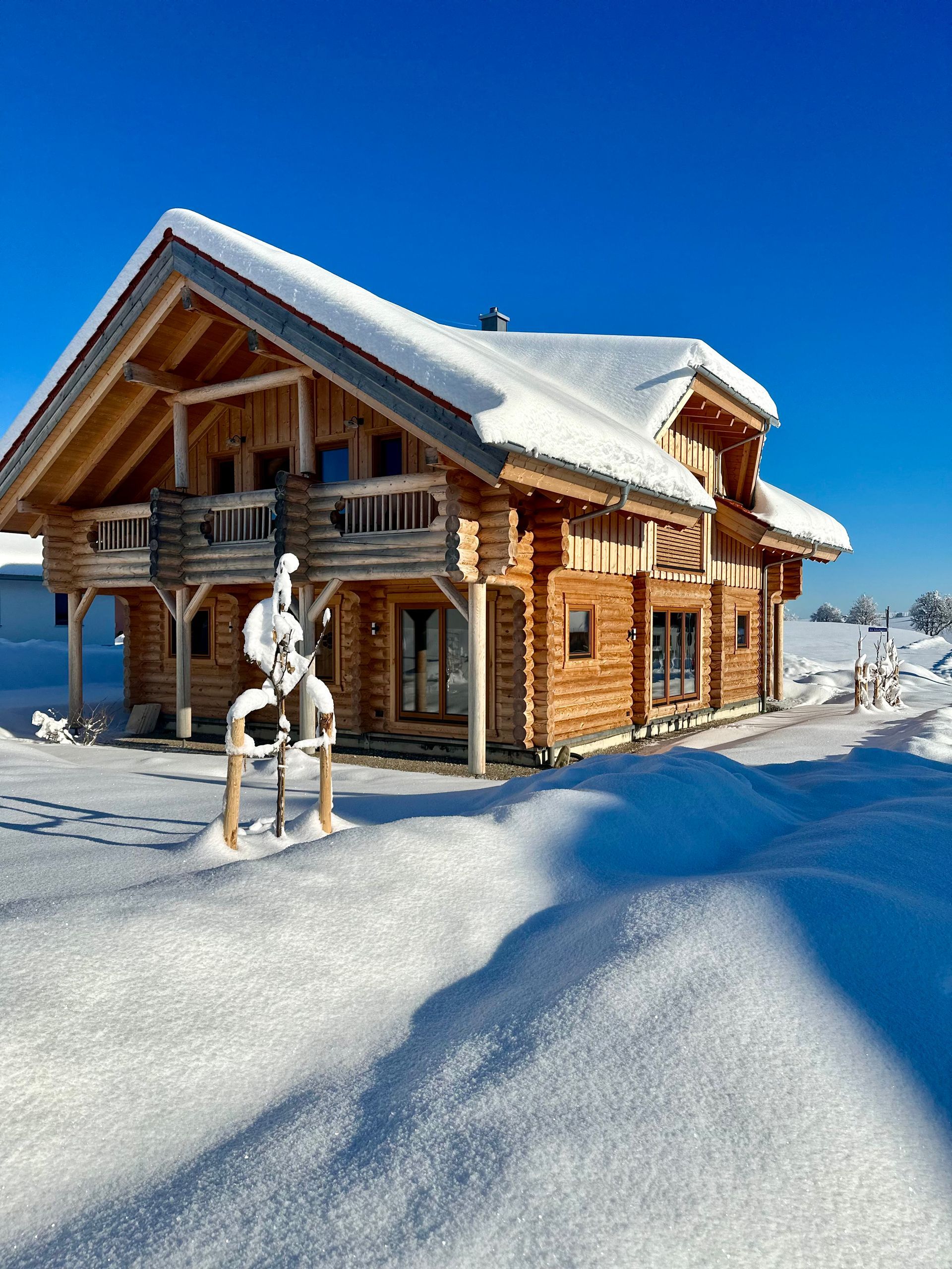 Eine schneebedeckte Holzhütte an einem sonnigen Wintertag.
