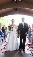 Bride and groom walking down a petal-lined aisle in a bright church