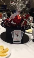 Black tabletop centerpiece with red and silver decorations, a menu card, and lemon slices on a white table