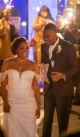 Bride and groom smiling and walking through a sparkler-lit wedding reception