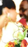 Blurred people beside a bouquet of red, yellow, and green flowers in warm light