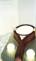 Brown leather dog collar on a green patterned surface with two white cups nearby