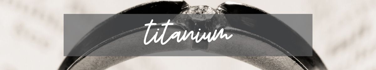 A black arched sign with white cursive text reading “titanium” on a gray background.