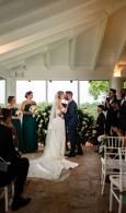Wedding couple kissing at the altar in a white tent, with guests seated on either side