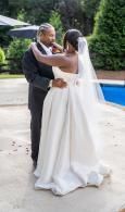 Bride and groom embrace beside a blue pool at an outdoor wedding venue