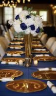 Elegant banquet table with blue runner, gold chargers, and white-and-blue floral centerpiece