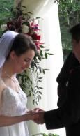 Bride holding hands during wedding ceremony beside a floral arrangement