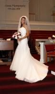 Bride in a white gown standing on red-carpeted church steps holding a bouquet.