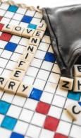 Scrabble tiles spelling “LOVE” and “EVERY” on a board beside a black bag