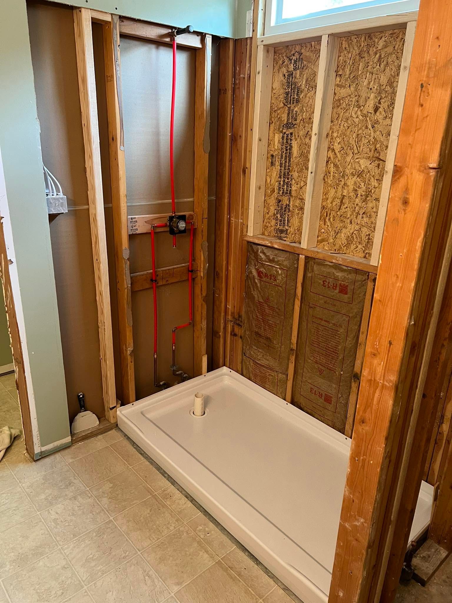 Partially framed bathroom with a white bathtub, exposed studs, plumbing, and unfinished walls