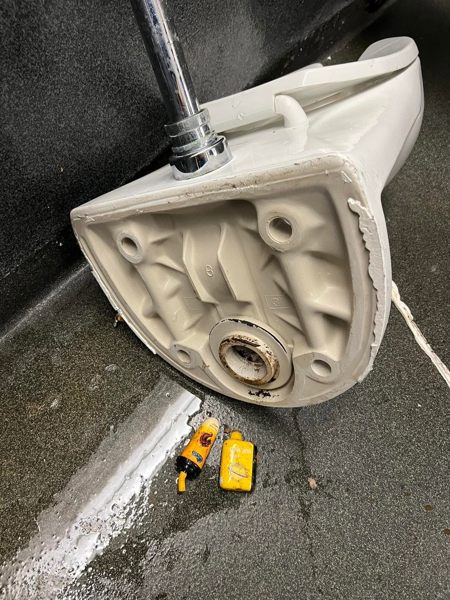 Close-up of a white wall-mounted shower fixture with tools and a yellow level on the wet floor below