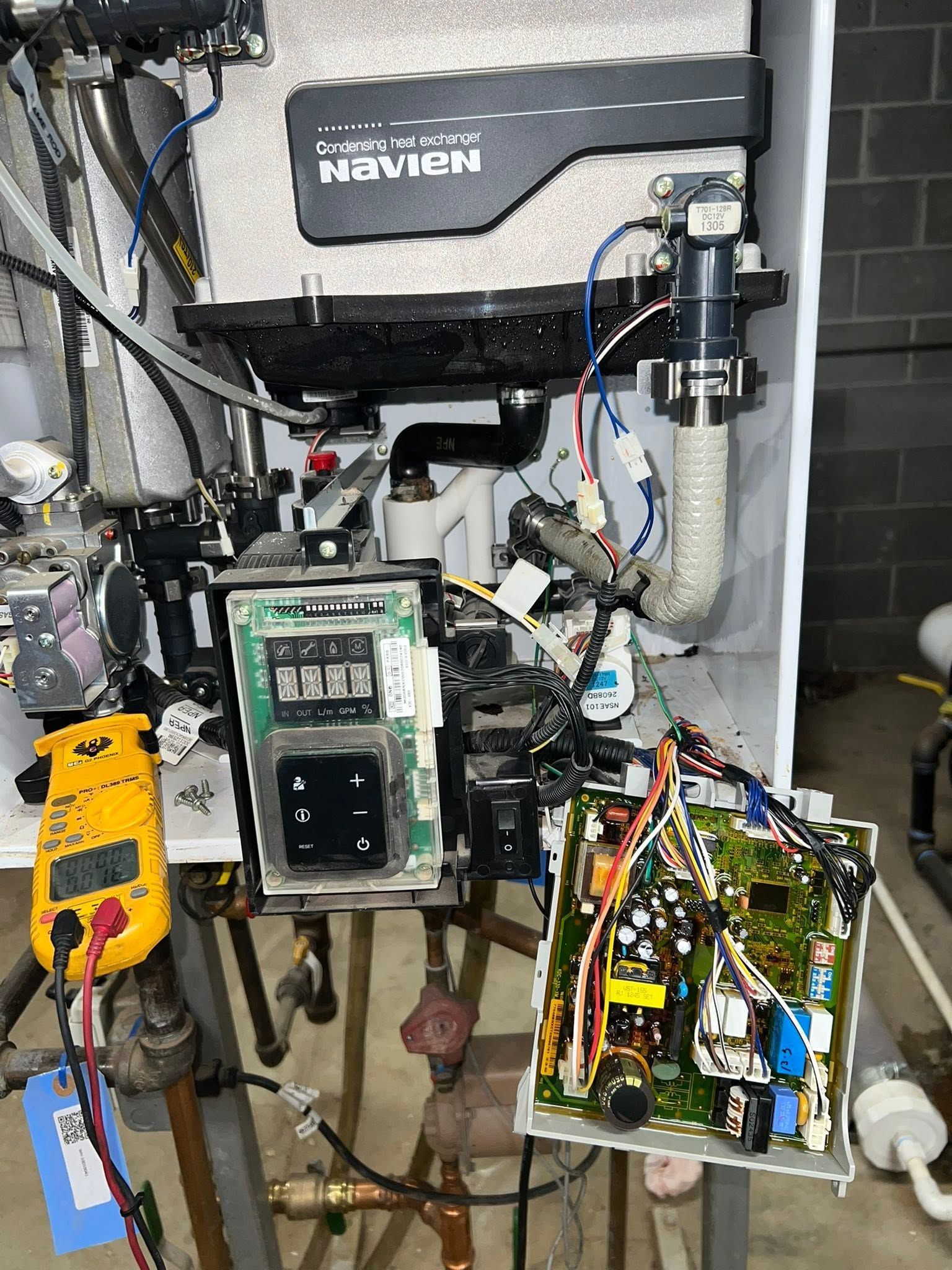 Open machine cabinet with tangled wiring, circuit boards, and mounted electronic modules inside.