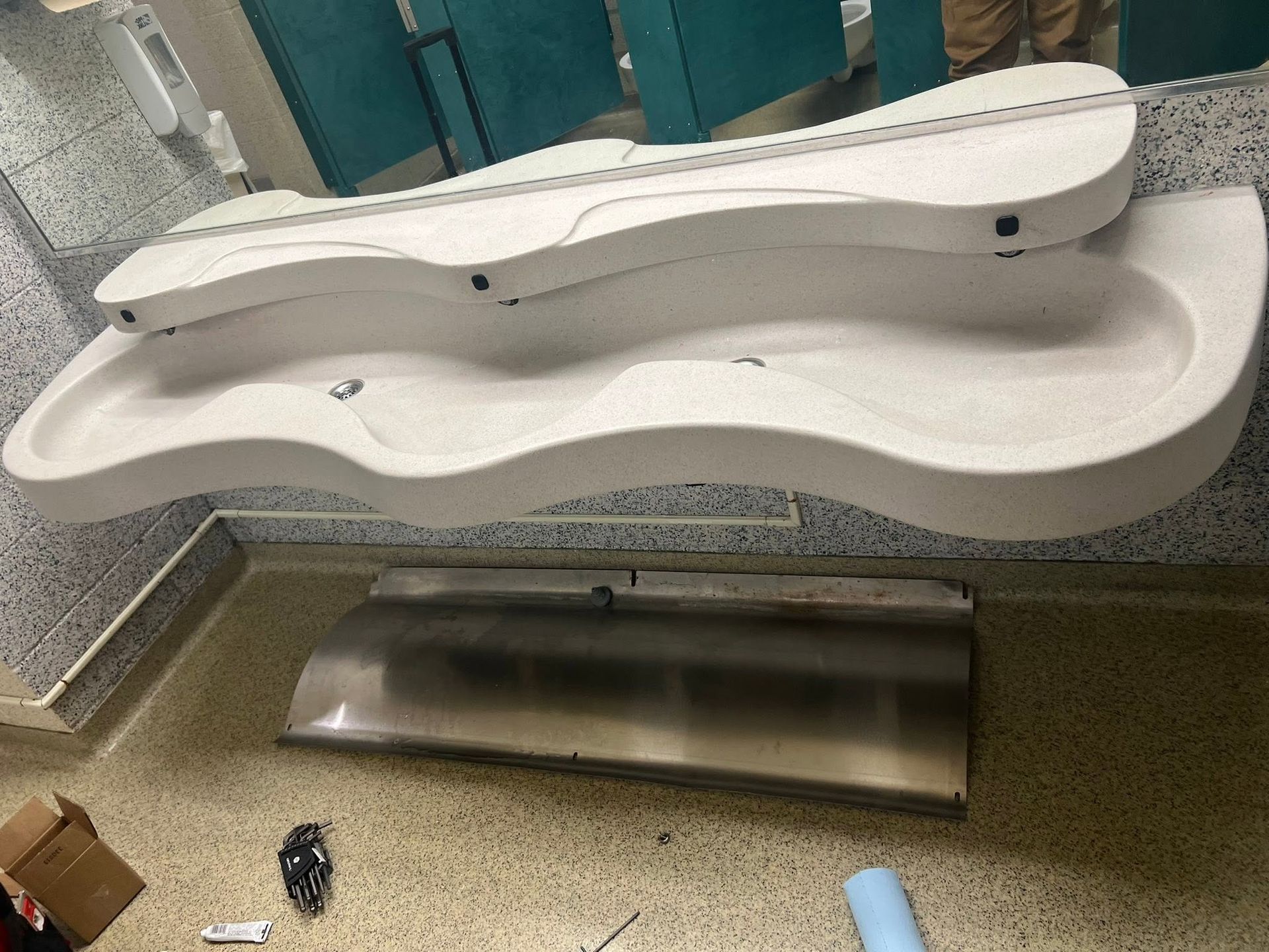 Modern public restroom with white accessible changing table and stainless-steel support bench.