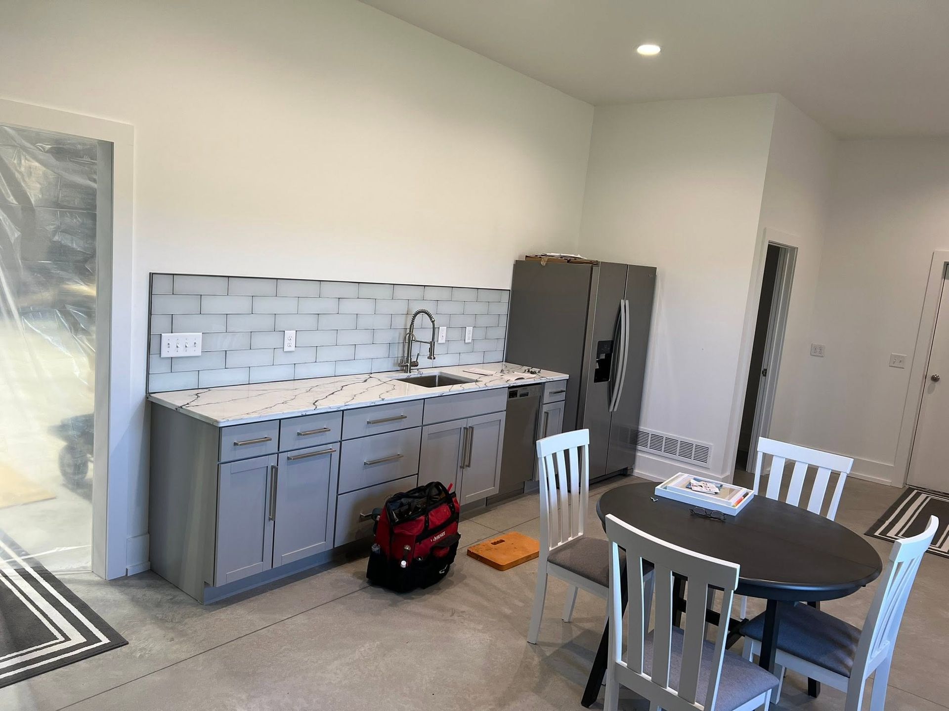 Modern kitchen and dining area with gray cabinets, white tile backsplash, and round table with chairs