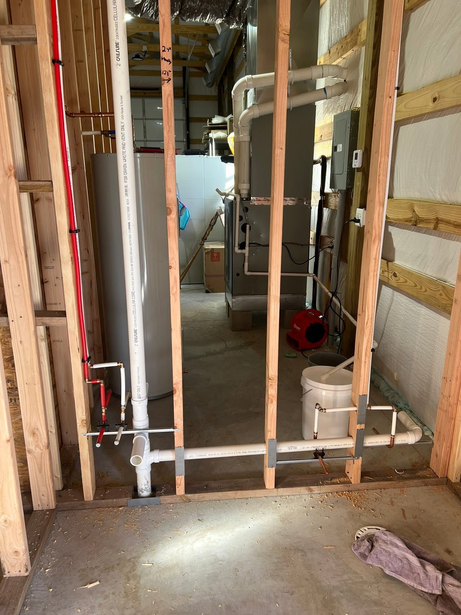 Framed doorway in unfinished interior with exposed studs, plumbing, and a light shining on the floor