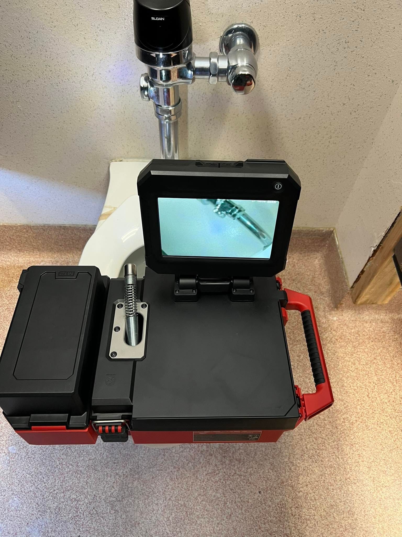 Open inspection case with monitor showing underwater pipe view beside a sink faucet