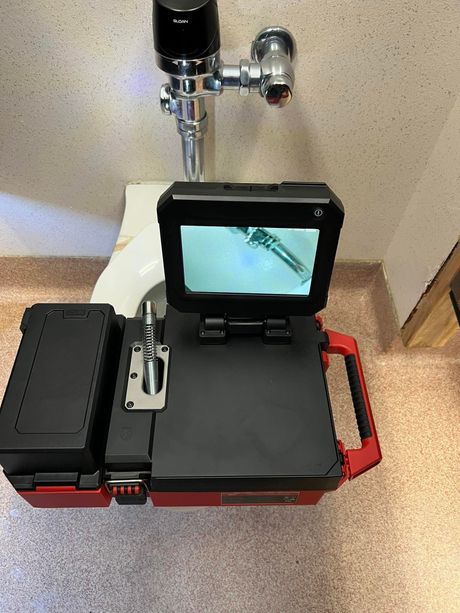 Open inspection case with monitor showing underwater pipe view beside a sink faucet