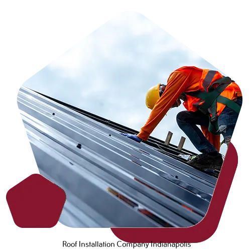 A worker in safety gear installs a metal roof on a building under a bright, cloudy sky.