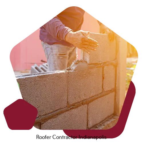 A person laying grey concrete blocks to build a wall outdoors.