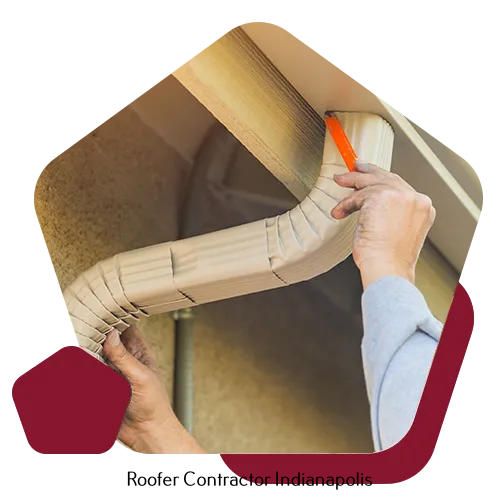 A contractor installs a beige gutter component against the roof eaves of a house.