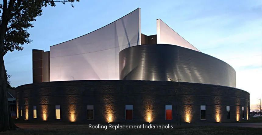 A modern building with curved stone walls and dramatic, illuminated metal towers at dusk in Indianapolis.