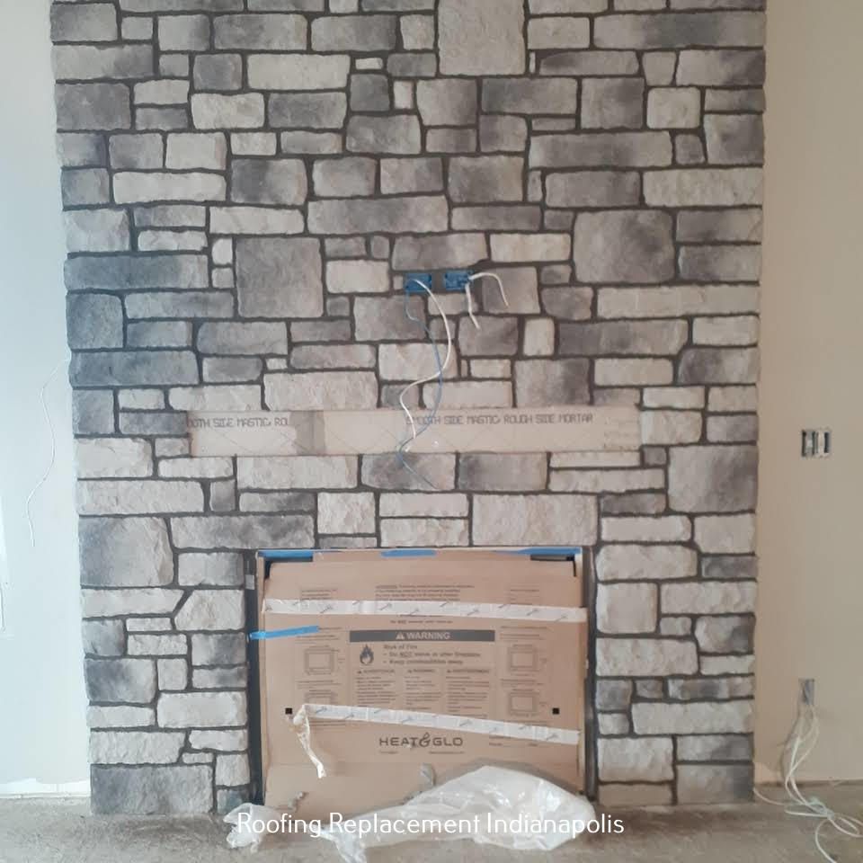 A gray stone fireplace under construction, featuring an unfinished mantel and a cardboard-covered fireplace insert.