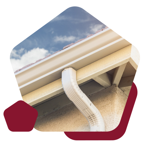 A close-up view of a white metal downspout connected to a house gutter against a sky background.