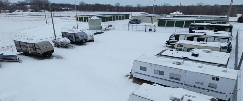 A row of trailers are parked in the snow in a parking lot.