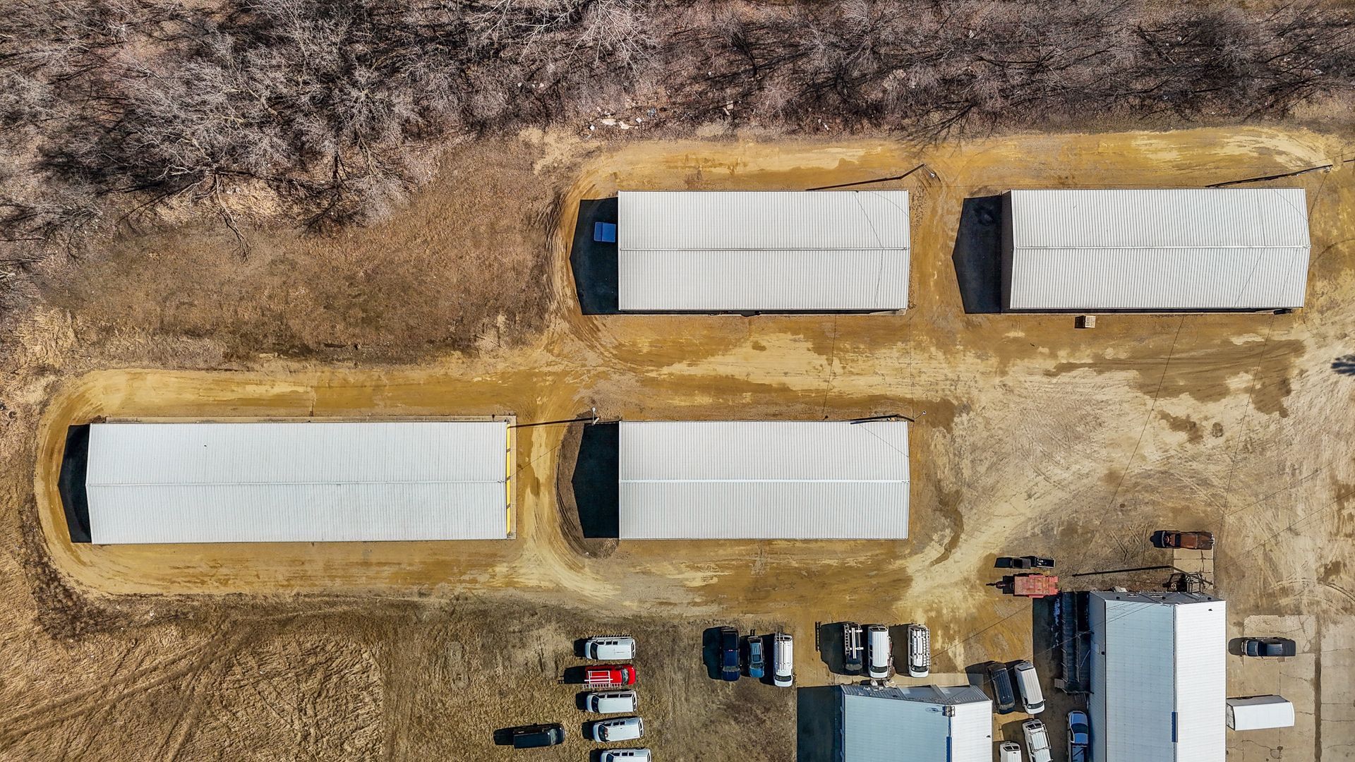 An aerial view of a row of trailers parked in a field.