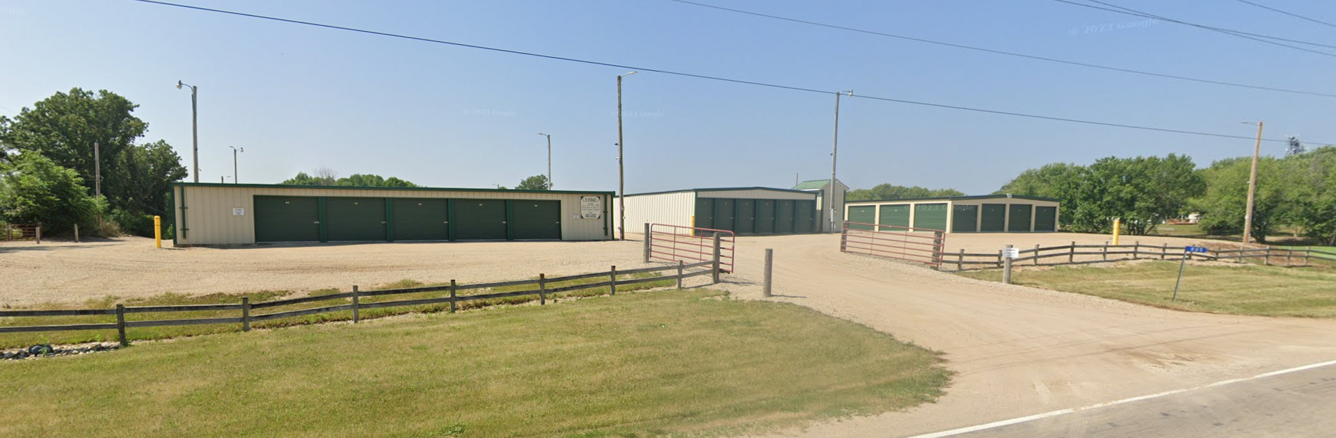 A dirt road leading to a building with a fence around it