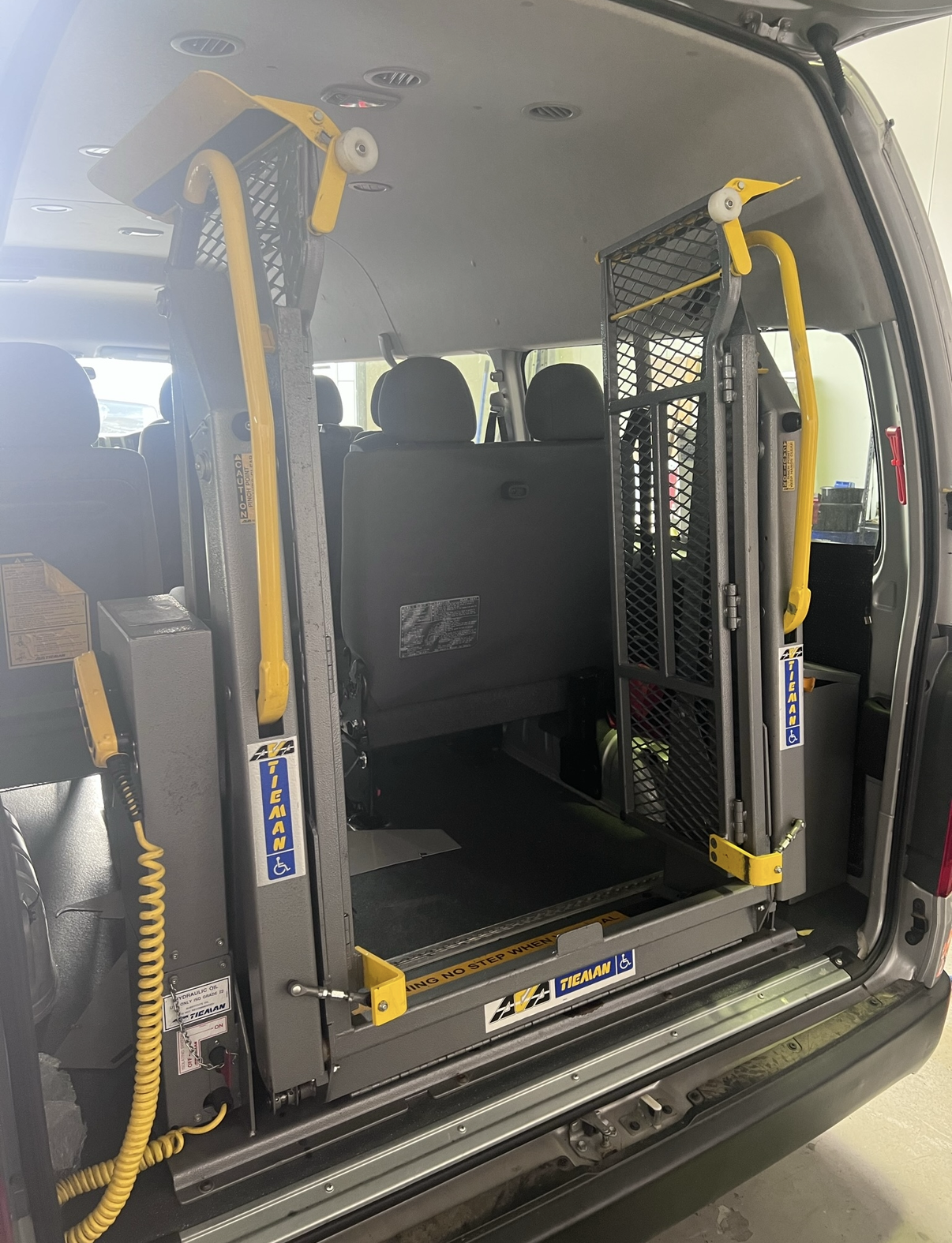 Inside of a van with a wheelchair lift, showing the lift in its folded-up position, ready for wheelchair access.