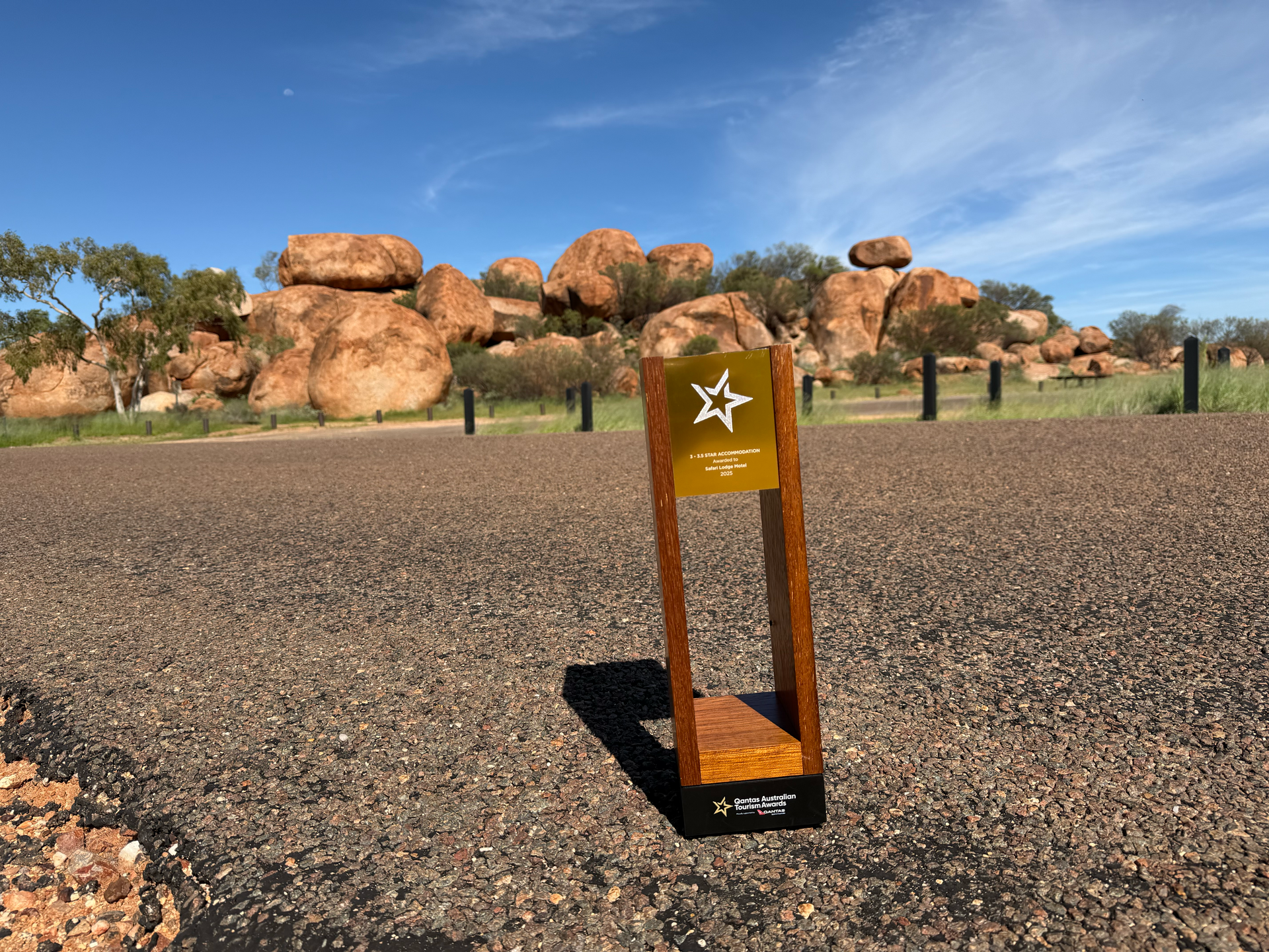 Gold award plaque in a rocky outdoor landscape under a blue sky