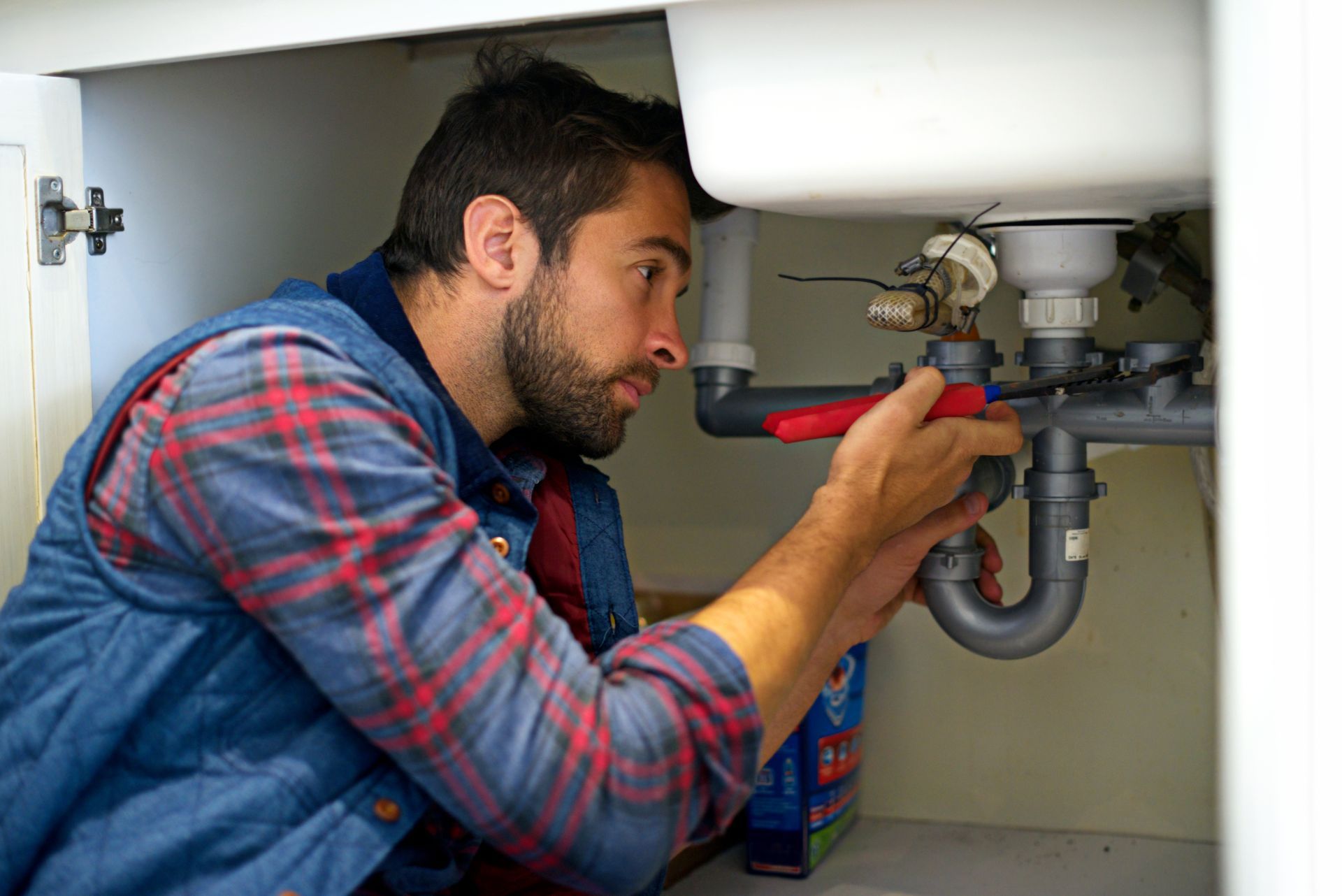 Plumber is Fixing a Sink Pipe with a Wrench — Scotts Valley, CA — George Allen & Sons Inc. Plumbing Plumber is Fixing a Sink Pipe with a Wrench — Scotts Valley, CA — George Allen & Sons Inc. Plumbing