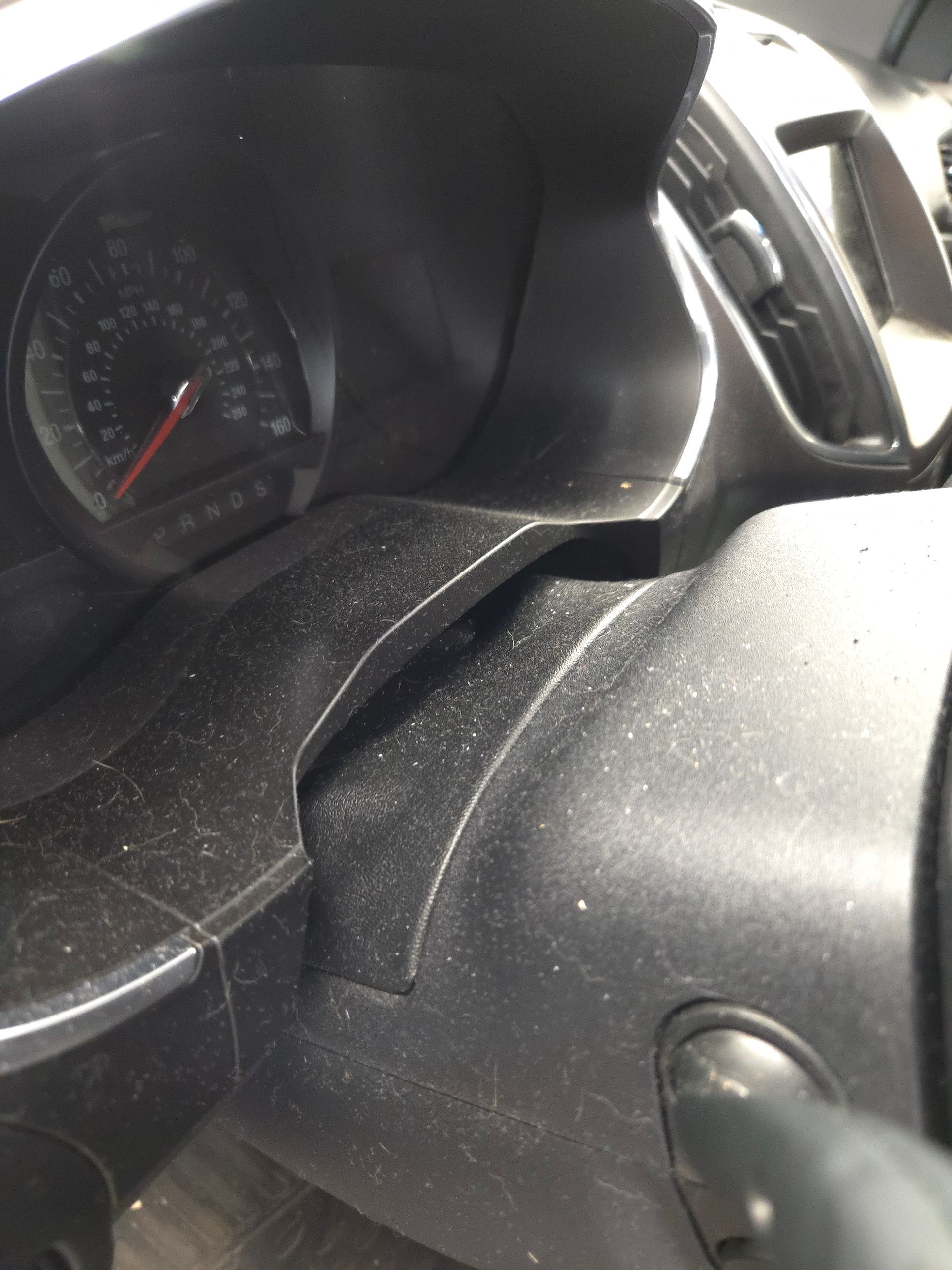 Person wearing black glove cleaning a black car steering wheel with soap and brush.