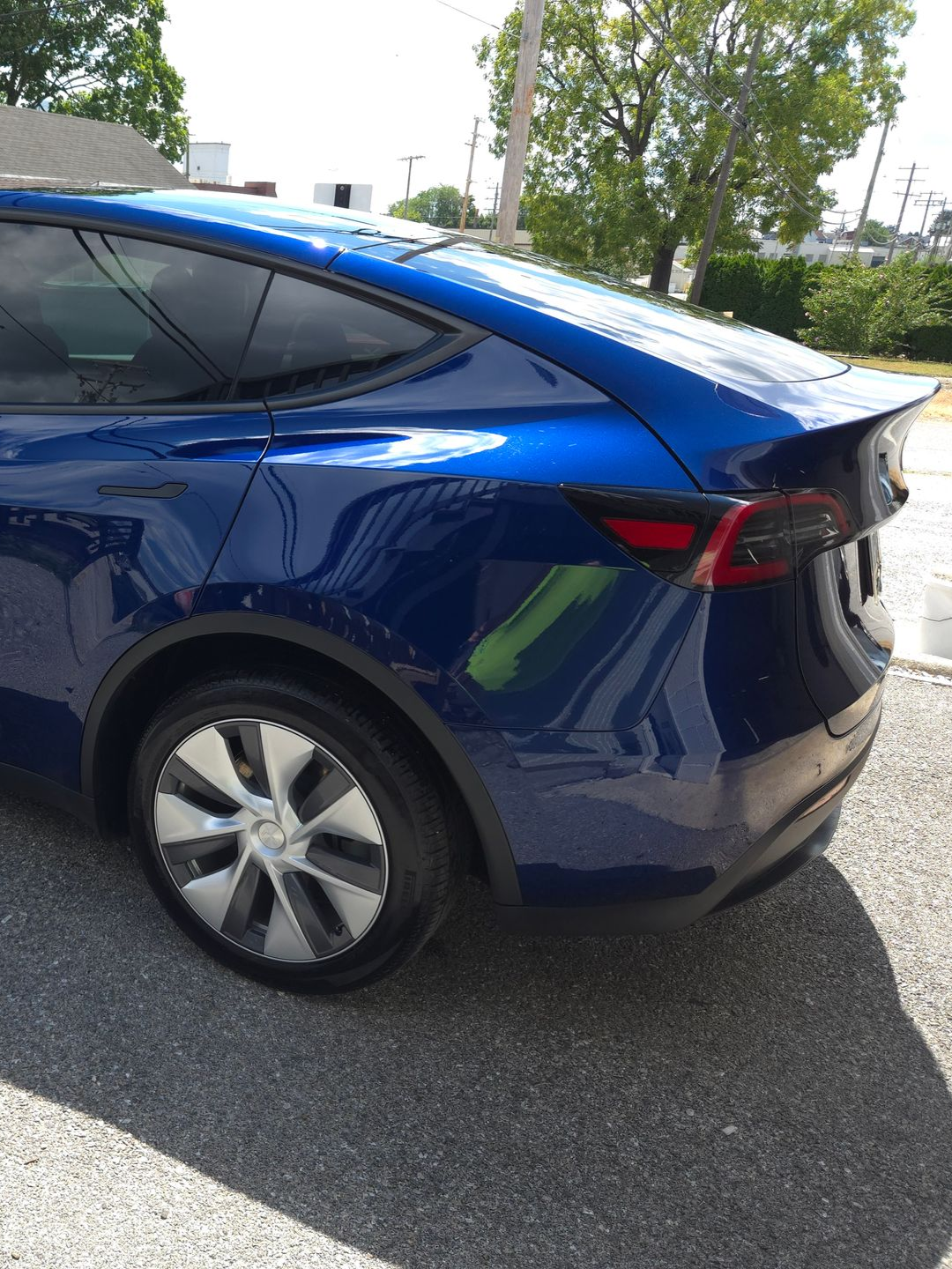 Blue Tesla Model Y, rear view, parked outdoors.