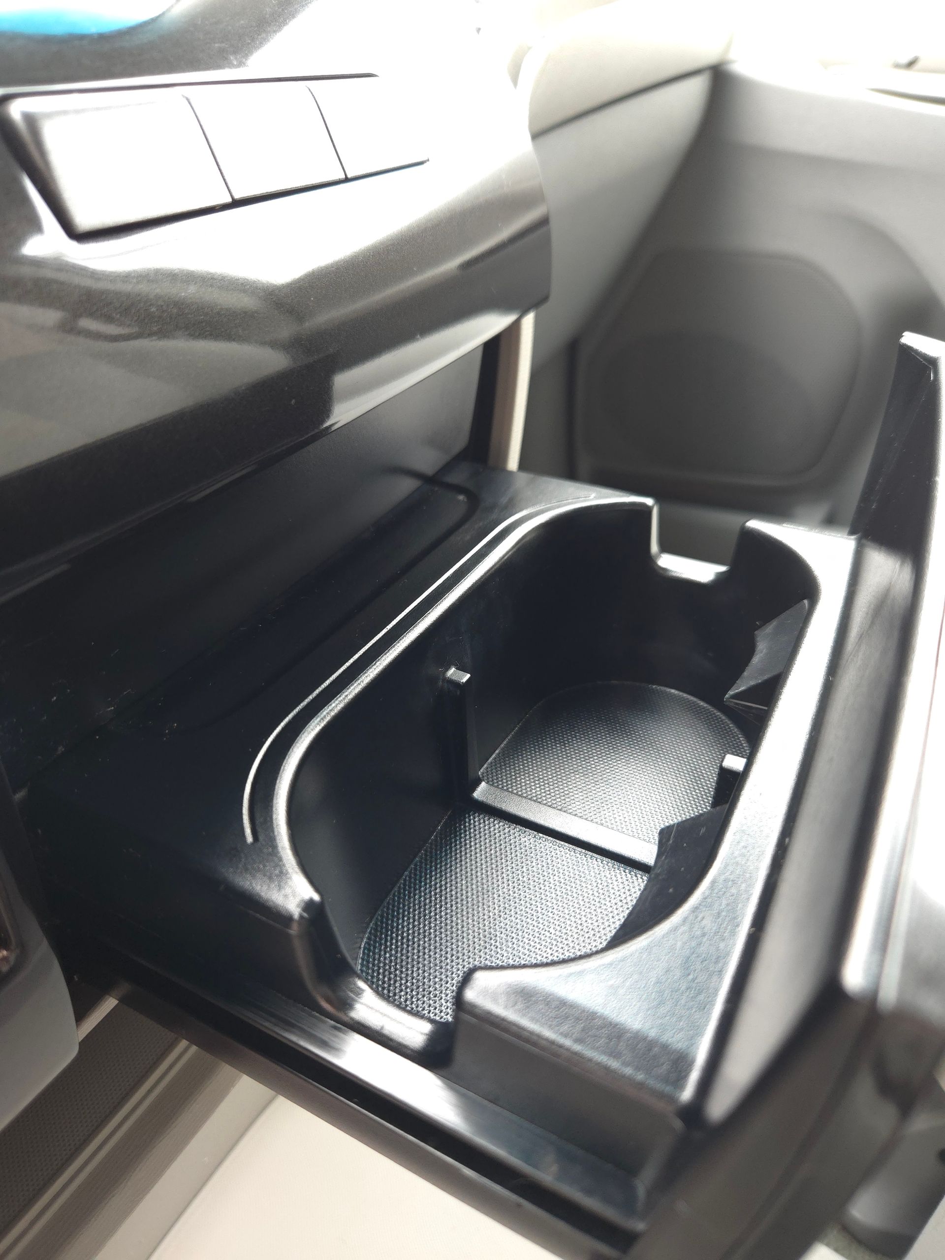 Black car cup holder with a textured bottom and a silver trim.